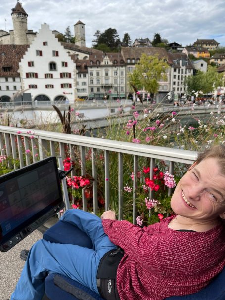 Nele Diercks mit ihrem Sprachcomputer auf einer Terrasse in Schaffhausen, im Hintergrund die Altstadt