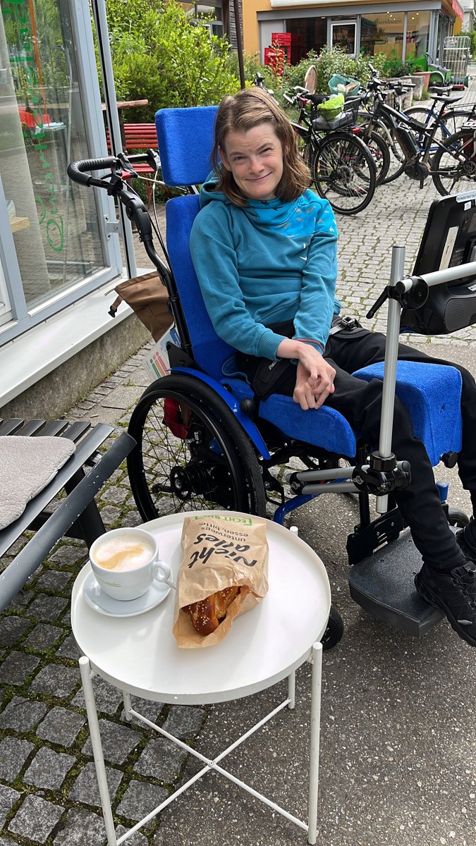 Nele Diercks sitzt lächelnd an einem Tisch im Freien
