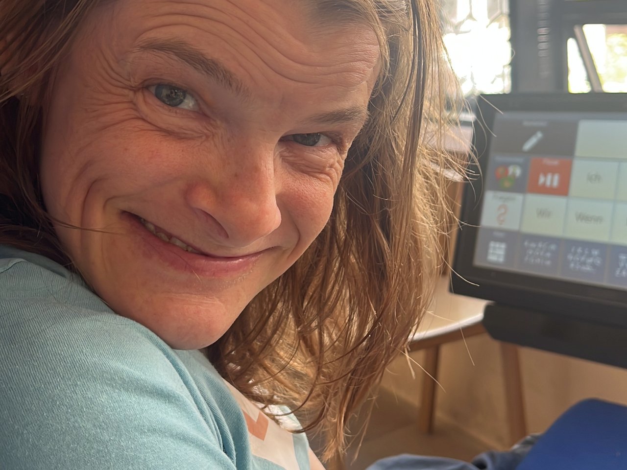 Nele Diercks l&auml;chelt, neben ihr ihr augengesteuerter Sprachcomputer