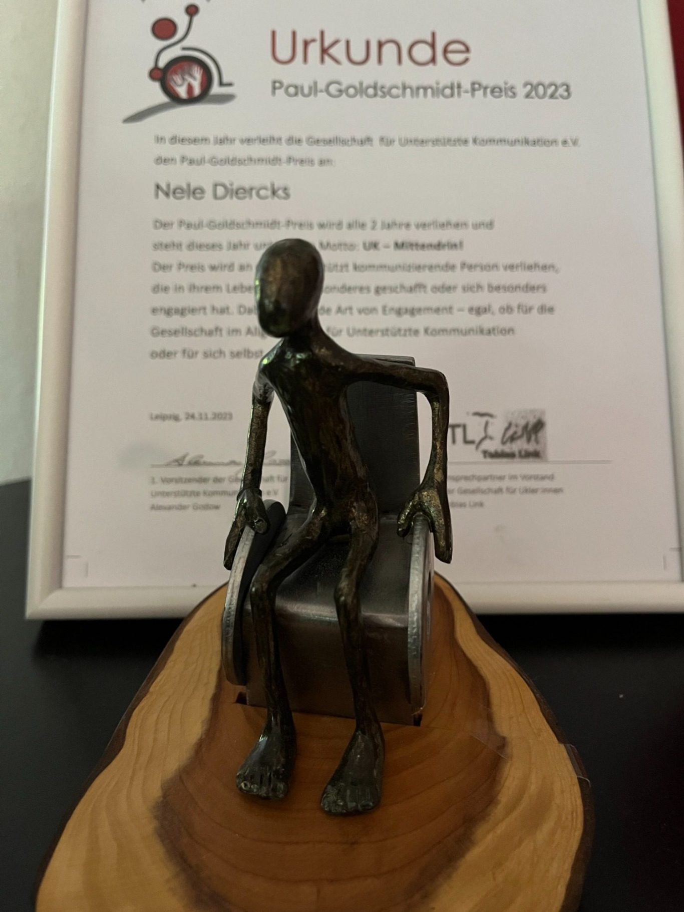 Urkunde des Paul-Goldschmidt-Preises 2023 f&uuml;r Nele Diercks mit der Bronze-Skulptur einer Person im Rollstuhl